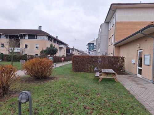 a park with a wooden bench next to a building at Apartment Hundige in Greve