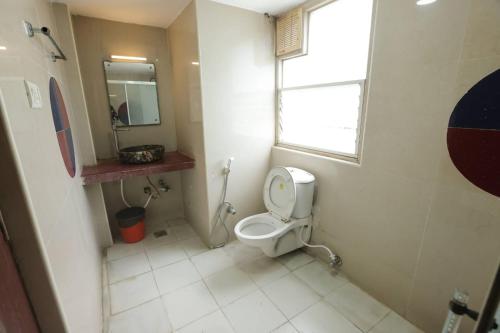 a bathroom with a toilet with a window and a mirror at GOLDMINE HOTELS in Chennai