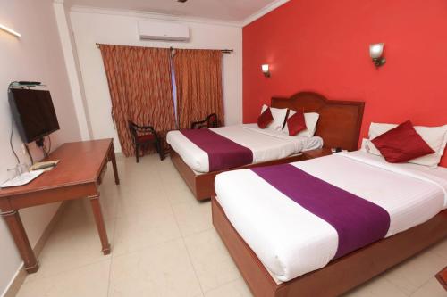 a hotel room with two beds and a desk and a television at GOLDMINE HOTELS in Chennai