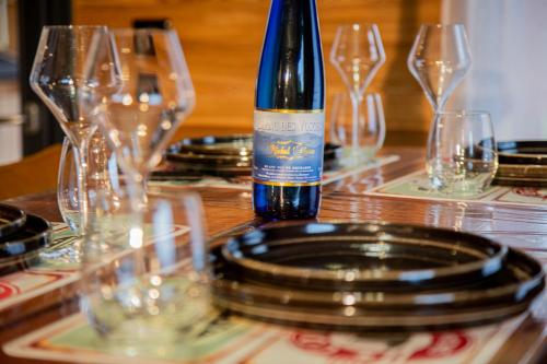 a bottle of wine sitting on a table with glasses at Domaine de la vôge & chalets et spa in Xertigny