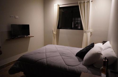 een slaapkamer met een bed, een raam en een televisie bij Eclectic Home in Lima