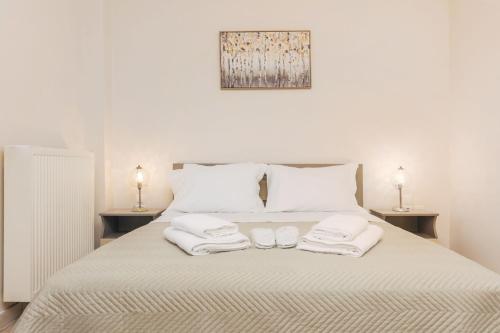uma cama branca com duas toalhas e duas lâmpadas em Sami's Apartment em Ambelókipoi