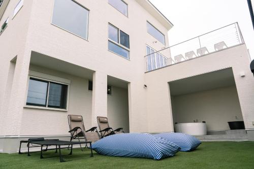 a house with two chairs and a table in the yard at ヴィランス淡路島 in Sumoto