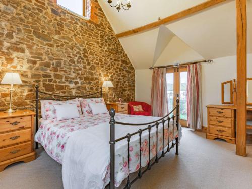a bedroom with a bed and a brick wall at 4 Bed in High Bickington BCOUR in Burrington