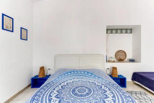 a bedroom with a bed with a blue and white bedspread at Domu Prexada B&B in Maracalagonis