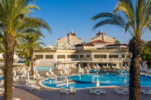 a large hotel with palm trees and a swimming pool at Aydinbey Famous Resort in Belek