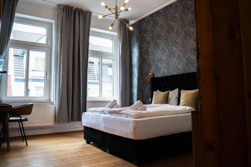 a bedroom with a bed and two windows at JUNIK Apartments - Deine Cityapartments in Duisburg in Duisburg