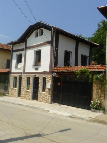 a large white house with a garage at Стаи под наем "При горските" in Troyan