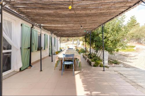 a patio with a table and chairs under a pergola at Domu Prexada B&B in Maracalagonis