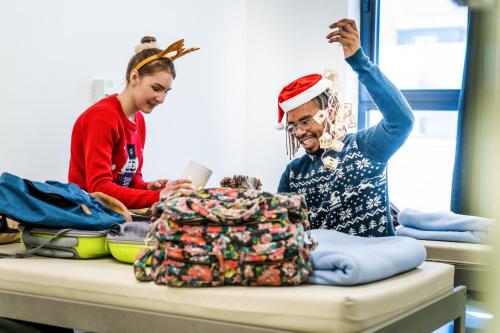 two women dressed in christmas attire looking at a bag at De Ploate Hostel in Ostend