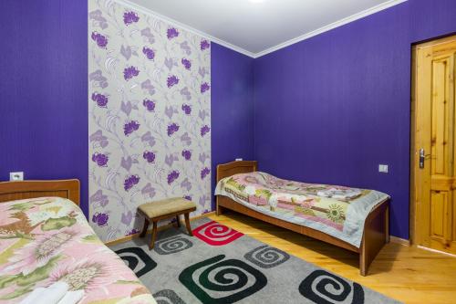 1 Schlafzimmer mit 2 Betten und lila Wänden in der Unterkunft Bokneti - Guest House, Agro Tourism Destination in Kʼareli