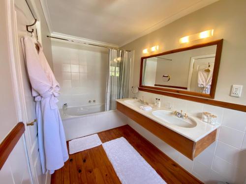 a bathroom with a sink and a tub and a mirror at Acorn House in Cape Town