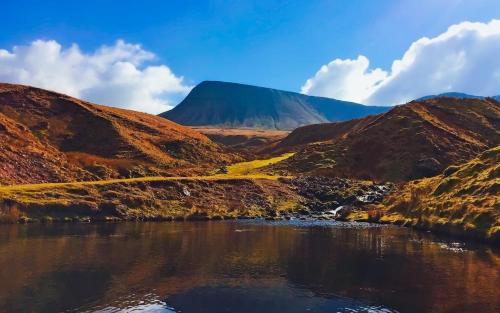 a view of a mountain with a body of water at Riverside in Brecon