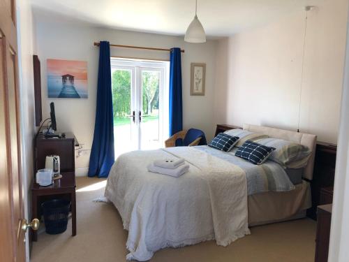 um quarto com uma cama com cortinas azuis e uma janela em Offa's Dyke Lodge B&B em Gladestry