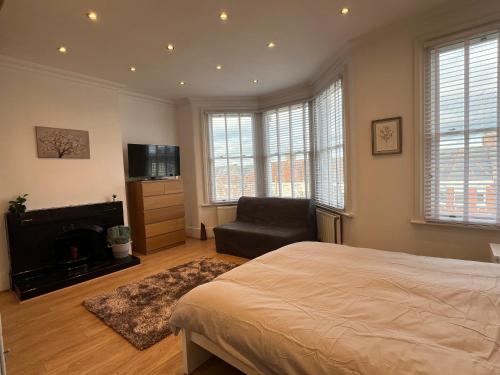 a bedroom with a bed and a chair and a television at 4 bed house 10 min walk to Tube in London