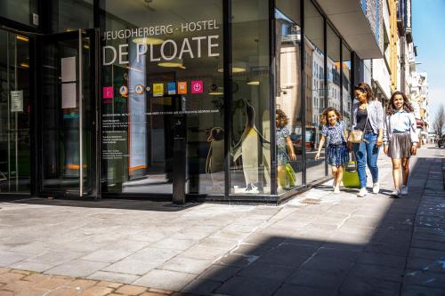 a group of people walking down a street in front of a store at De Ploate Hostel in Ostend