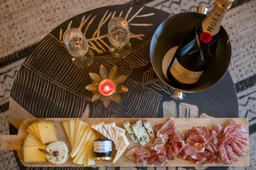 a table topped with a bottle of wine and cheese at MAISON AVEC SPA PRIVATIF ( JACUZZI ET SAUNA) in Bailleval