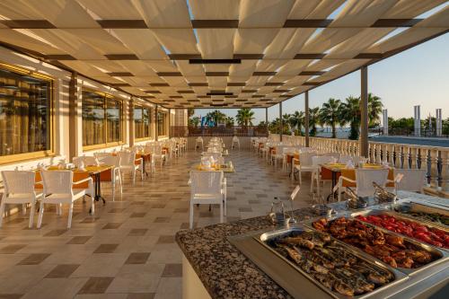 um restaurante com mesas e cadeiras e comida no chão em Aydinbey Famous Resort em Belek