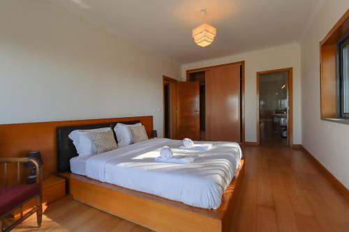 a bedroom with a large bed with white sheets at The Ocean View Villa in Viana do Castelo