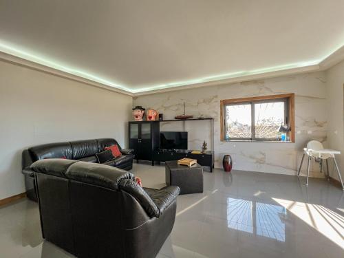 a living room with a leather couch and a television at The Ocean View Villa in Viana do Castelo