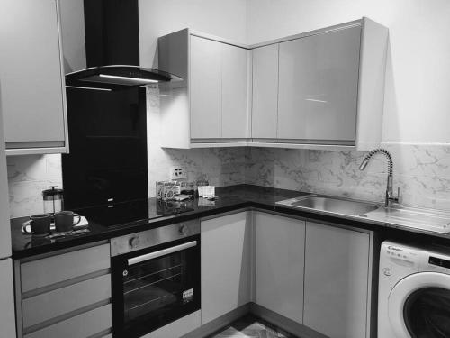 uma cozinha com armários brancos e uma máquina de lavar roupa em High Street, 2 bed, newly refurb em Leamington Spa