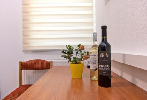 a bottle of wine sitting on a table with a plant at Apartmani Sebastijan in Banja Luka