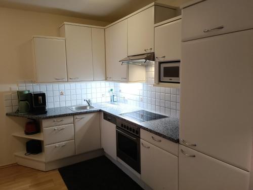 a kitchen with white cabinets and a sink and a stove at Schusslerhof in Sankt Leonhard im Pitztal