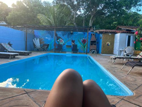 una persona tumbada en el suelo junto a una piscina en POUSADA SOL DE VERÃO - Cumuruxatiba -BA, en Cumuruxatiba
