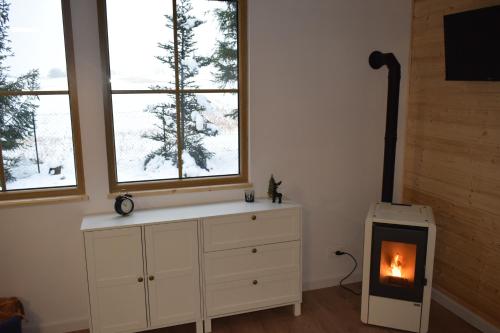 a room with a dresser with a fireplace and two windows at Activfarm domki na Kaszubach /domek Madzia in Lipnica