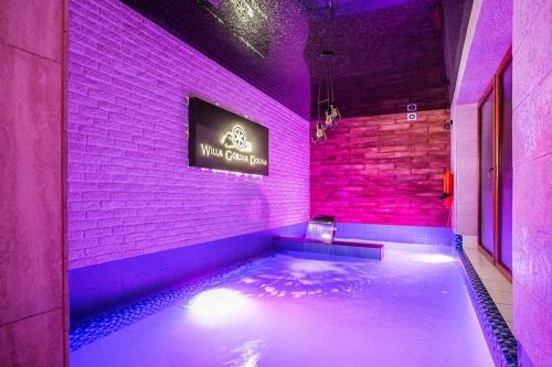 ポロニンにあるWilla Górska Dolina Jacuzzi & Saunaの紫色の照明が備わる客室内のホットタブ