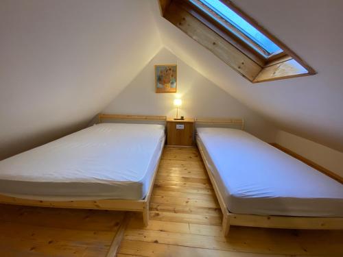 two beds in a attic bedroom with a skylight at Bele Staze Apartman 86 in Brzeće