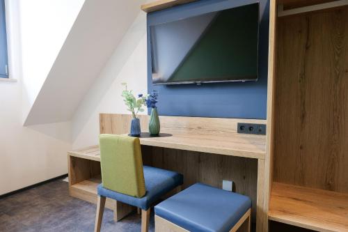um quarto com uma secretária, uma televisão e uma cadeira em Reos Hotel Isny em Isny im Allgäu
