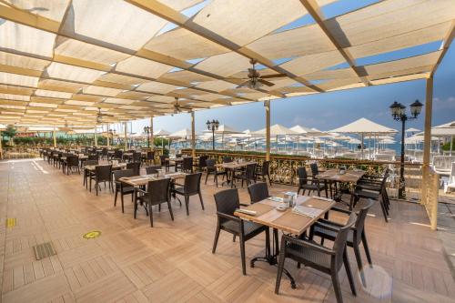 a restaurant with tables and chairs and a view of the ocean at Aydinbey Gold Dreams in Avsallar
