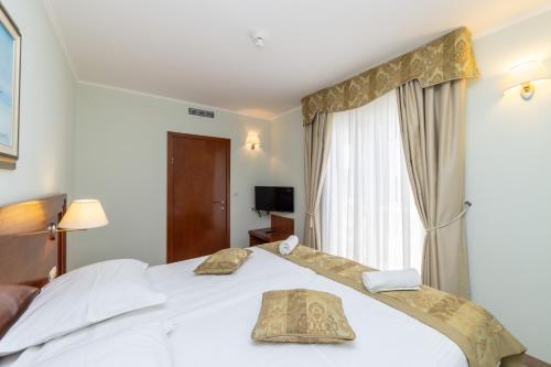 a bedroom with a white bed and a window at Hotel Bella Vista in Drvenik