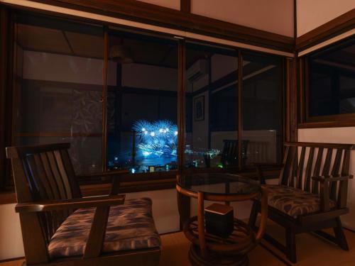 a room with two chairs and a glass table and a window at Atami Southern Wind　 熱海 南風楼(温泉付) in Atami