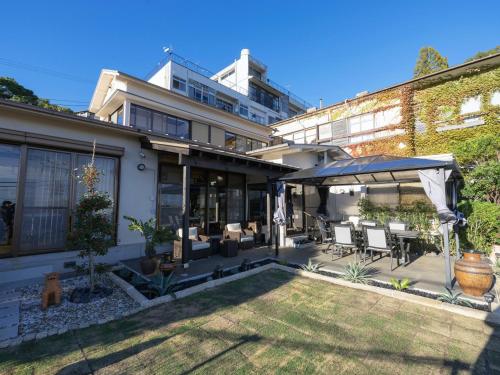 a house with a patio with chairs and an umbrella at Atami Southern Wind　 熱海 南風楼(温泉付) in Atami