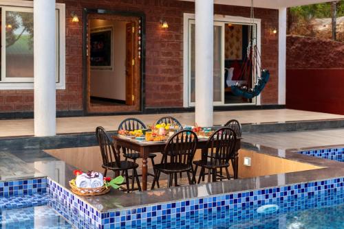 a table and chairs sitting next to a swimming pool at Malibu Villa by Hill Staytion in Panchgani