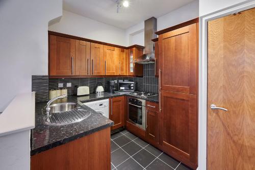 a kitchen with wooden cabinets and a counter top at Host & Stay - The Ivanhoe Retreat in Liverpool