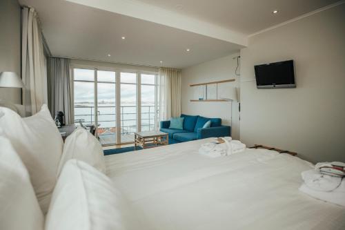 a bedroom with a large white bed and a blue chair at Gullmarsstrand Hotell & Konferens in Fiskebäckskil