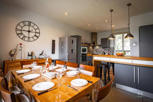 a kitchen and dining room with a table and a clock at Le Chevran - Conciergerie de la Yaute in Cluses