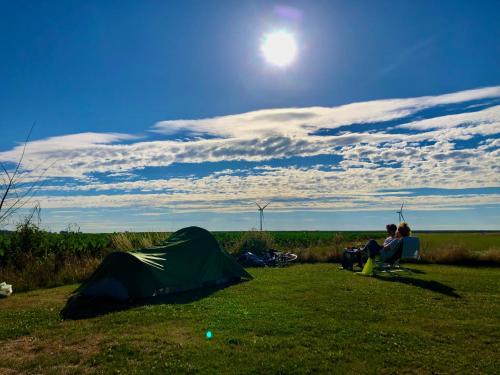 two people sitting in a field next to a tent at Camping 'de Val' in Zierikzee