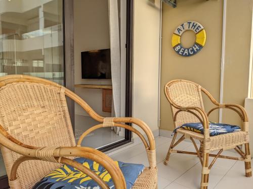 two wicker chairs and a clock on the wall at Seaview serenity apartment in Flic-en-Flac