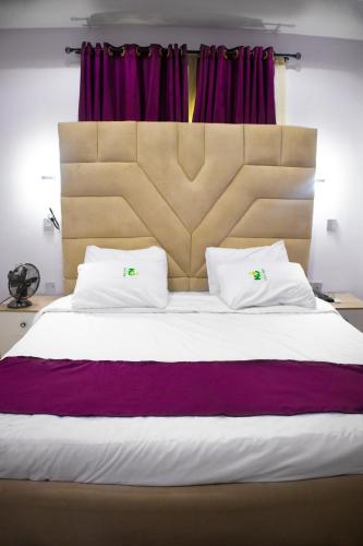 een slaapkamer met een groot bed met een groot hoofdeinde bij Klulead Garden and Suites in Ijebu Ode