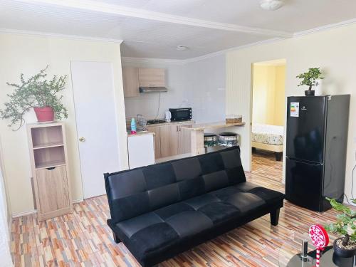 uma sala de estar com um sofá preto e uma cozinha em Departamento amoblado calama em Calama