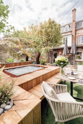 a backyard with a wooden deck with chairs and a table at La villa 10 HÔTEL SPA in Étretat