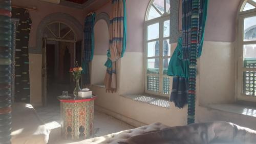 Habitación con ventanas y mesa con jarrón. en Riad Maizie, en Marrakech