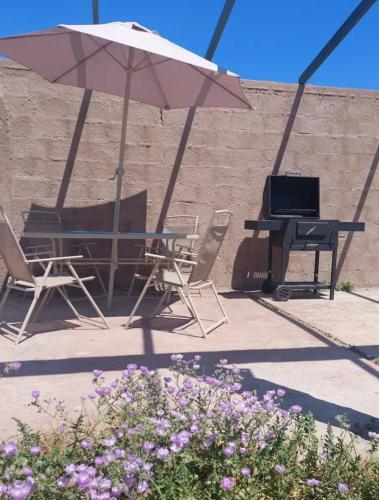 a table and chairs with a laptop and an umbrella at Refugio del Archipielago D4 in Punta de Choros