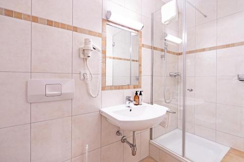 a white bathroom with a sink and a shower at Hotel Krone Tirol in Reutte