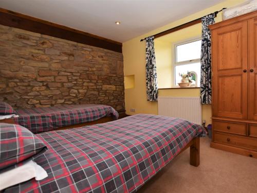 a bedroom with two beds and a stone wall at 4 Bed in Whaley Bridge PK535 in Whaley Bridge