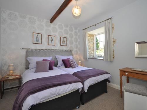 a bedroom with a large bed with purple pillows at 1 Bed in Bourton-on-the-Water 44961 in Withington